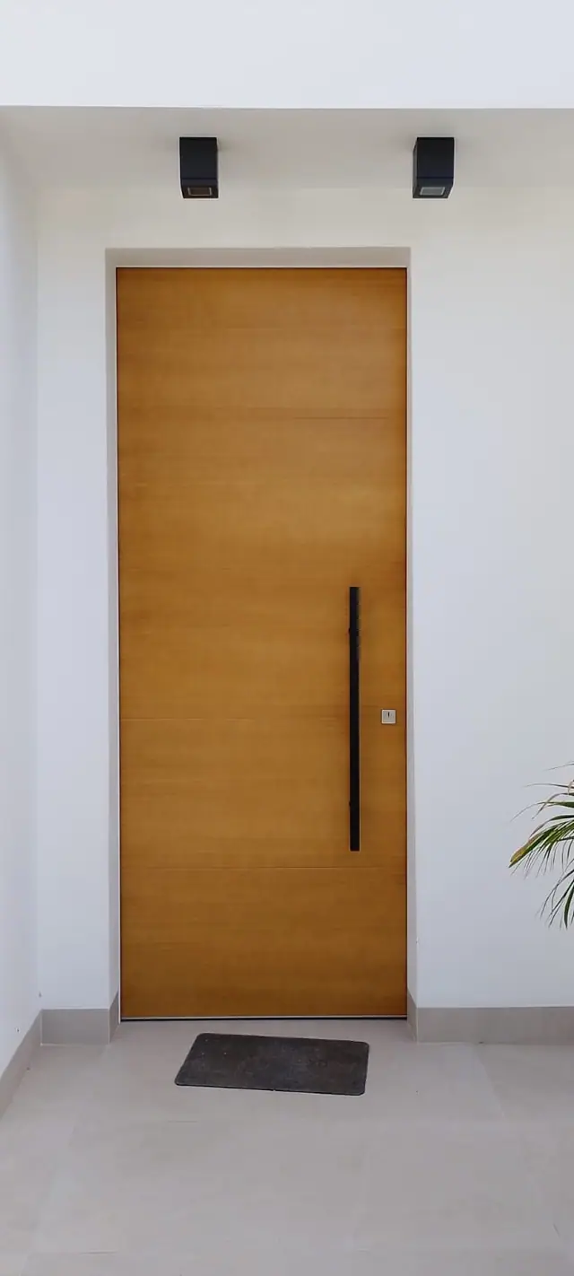 Puerta lisa en tono madera con tirador vertical negro. Trabajo de Hermanos Sánchez Soto Carpinteros, Medina-Sidonia (Cádiz)